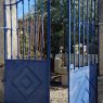 Ancien portail peint en bleu en fer forgé riveté à deux vantaux